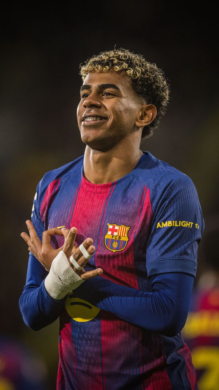 Lamine Yamal of FC Barcelona smiling and making a hand gesture (the '304' counting sign) with bandaged fingers, blue and red striped kit with the FCB crest.